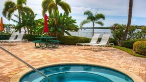 A swimming pool with lounge chairs and palm trees. - The Bayview a Quaint 1 1 Balcony on the bay (St. Petersburg)
