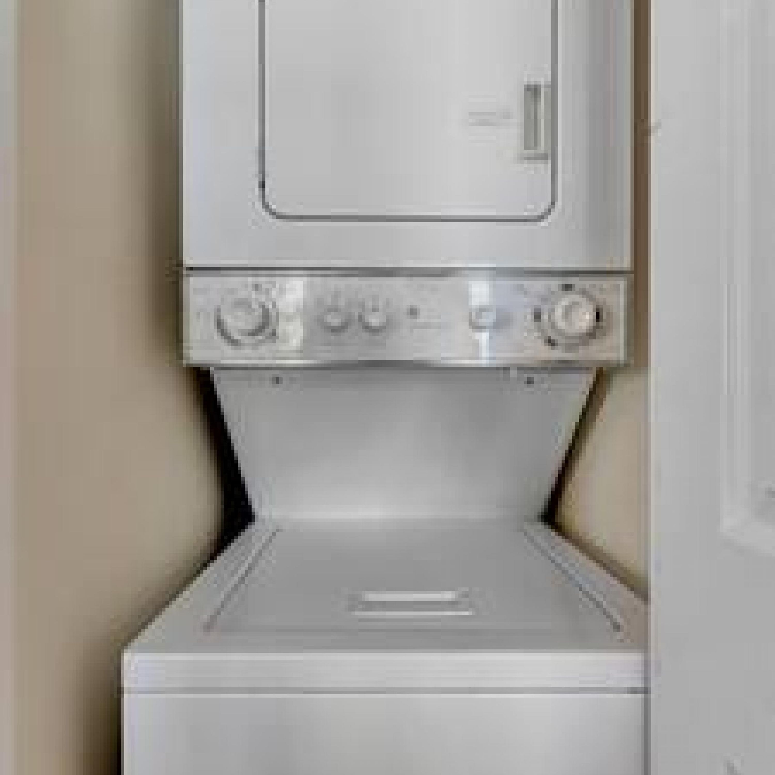A compact, white, wall-mounted washer and dryer unit with a control panel on top.