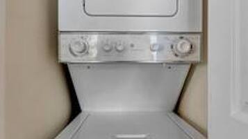 A compact, white, wall-mounted washer and dryer unit with a control panel on top.