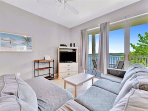 Relax in a comfortable seating area with a sofa, TV, and bookshelf, and enjoy the view from the balcony with a chair and table.