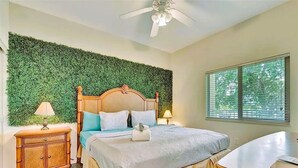 A bedroom with a bed, bedside tables, a nightstand, a ceiling fan, and a window with blinds. - The Bayview a Quaint 1 1 Balcony on the bay (St. Petersburg)