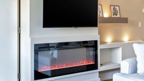 A modern living room with a flat-screen TV mounted above a glass-fronted fireplace.