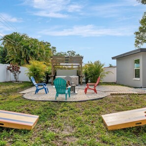An outdoor patio area with a wooden pergola, three Adirondack chairs, a table, and a barbecue grill. - 4b 2b w Hot Tub BBQ Firepit 9mins to Beach (Largo)