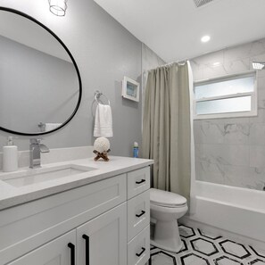 A modern bathroom with a white vanity, a round mirror, a toilet, and a bathtub. - 4b 2b w Hot Tub BBQ Firepit 9mins to Beach (Largo)
