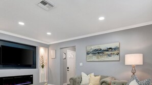 A modern living room with a flat-screen TV, fireplace, comfortable seating, and artwork on the wall.
