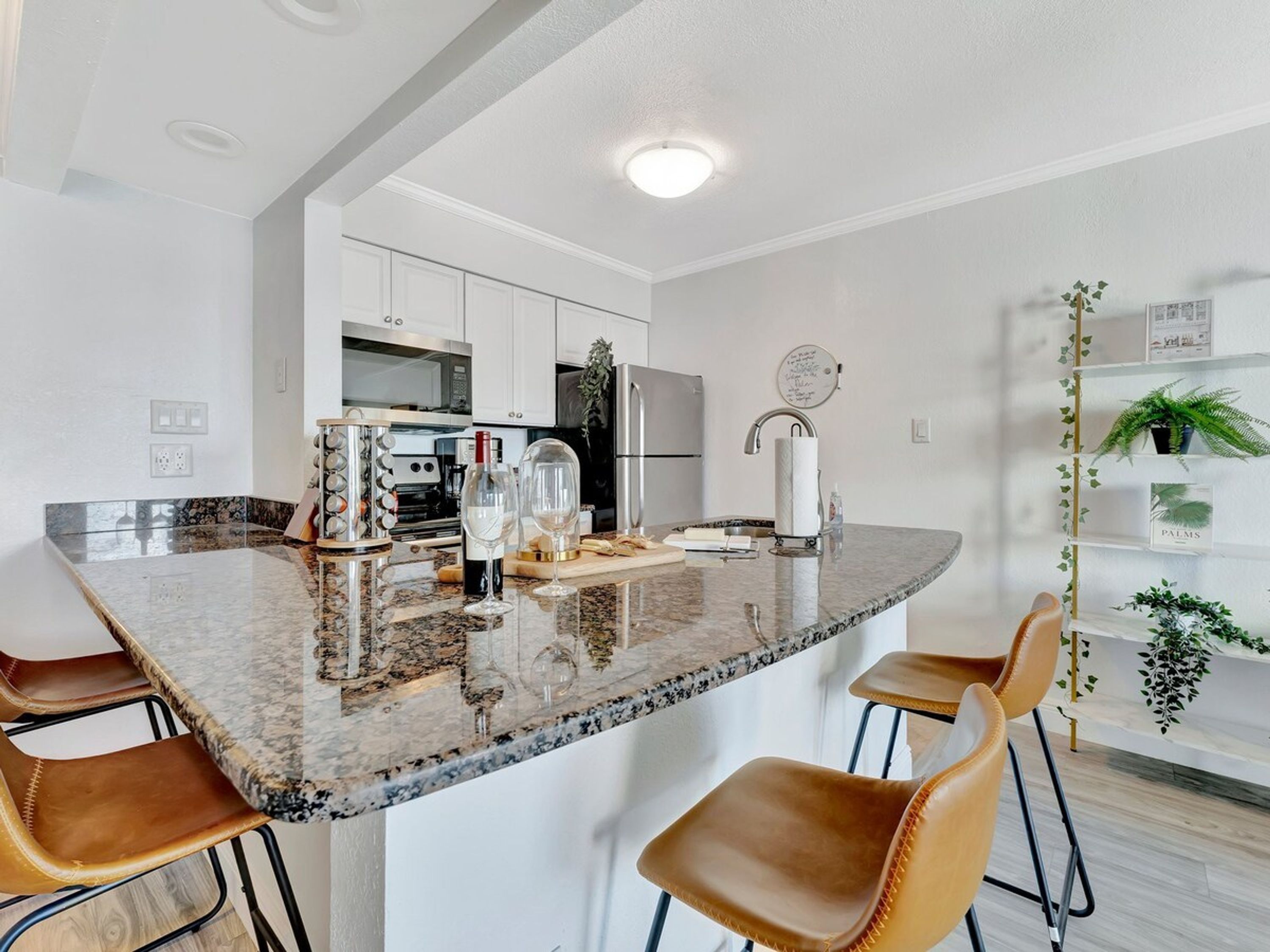 A modern kitchen with a granite countertop, stainless steel appliances, and a central island with bar stools.