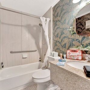 A bathroom with a bathtub, toilet, and shower. There is a first aid kit on the counter.