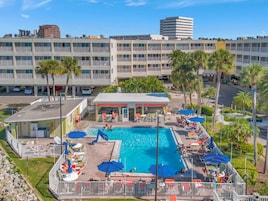 Ein Hotel mit Pool, umgeben von Palmen und einem Parkplatz.