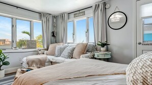 Ein modernes Schlafzimmer mit einem großen Bett, einem Nachttisch und Blick auf den Strand.