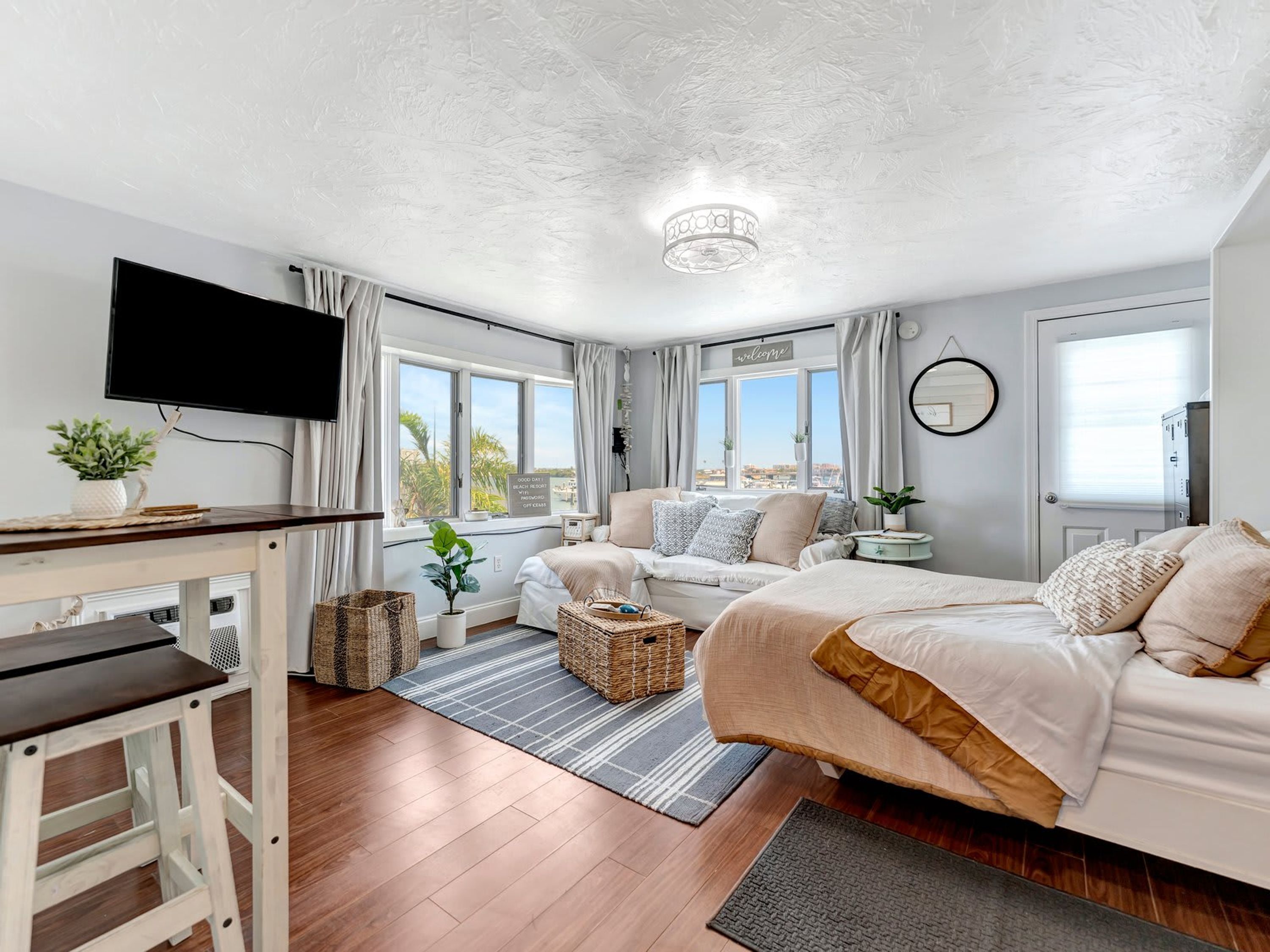 Une chambre à coucher avec un lit, un bureau, une télévision et une vue sur l’extérieur.