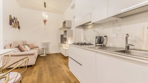 Una cocina moderna con gabinetes blancos, un protector contra salpicaduras de mármol y una estufa a gas.