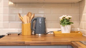 A kitchen counter with a kettle, wooden utensil holder, and a potted plant. - Short Walk to I360 and Beach 5 Condo With Patio (Brighton)
