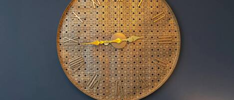A large, ornate wall clock with intricate patterns and Roman numerals.