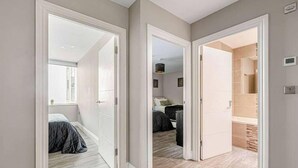 A hallway leading to a bedroom with a bed, a closet, and a bathroom. - Brighton Lanes Sea View 2BR AP (Brighton)