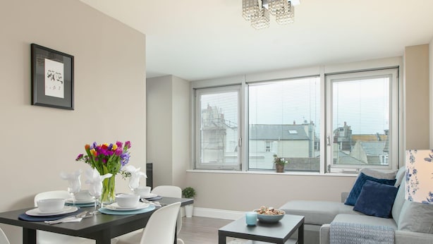 A modern living room with a dining area, large windows, and a view of the city. - Gorgeous 5 Star Location 2 min to Brighton Beach (Brighton)
