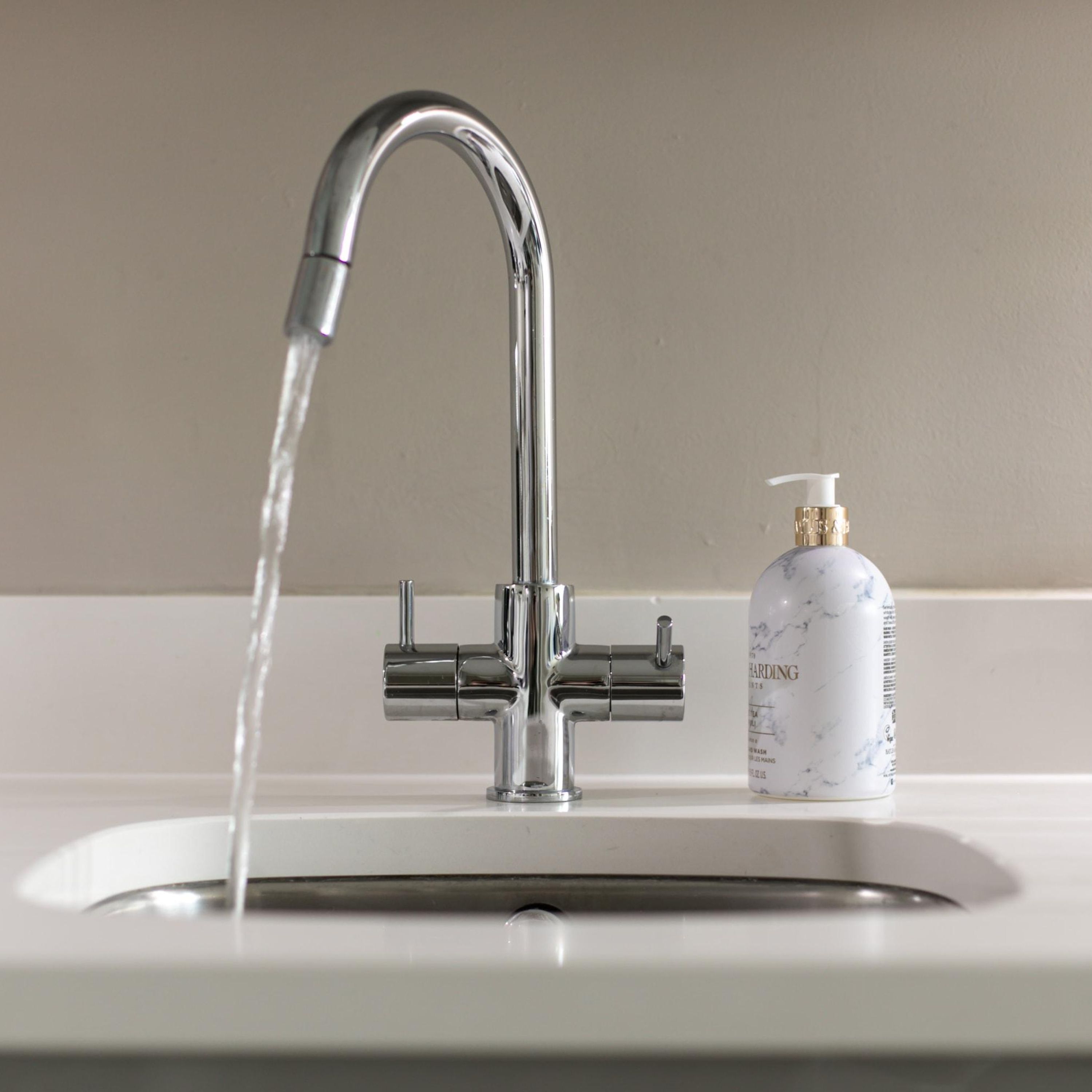 A modern bathroom sink with a chrome faucet and a bottle of hand soap.
