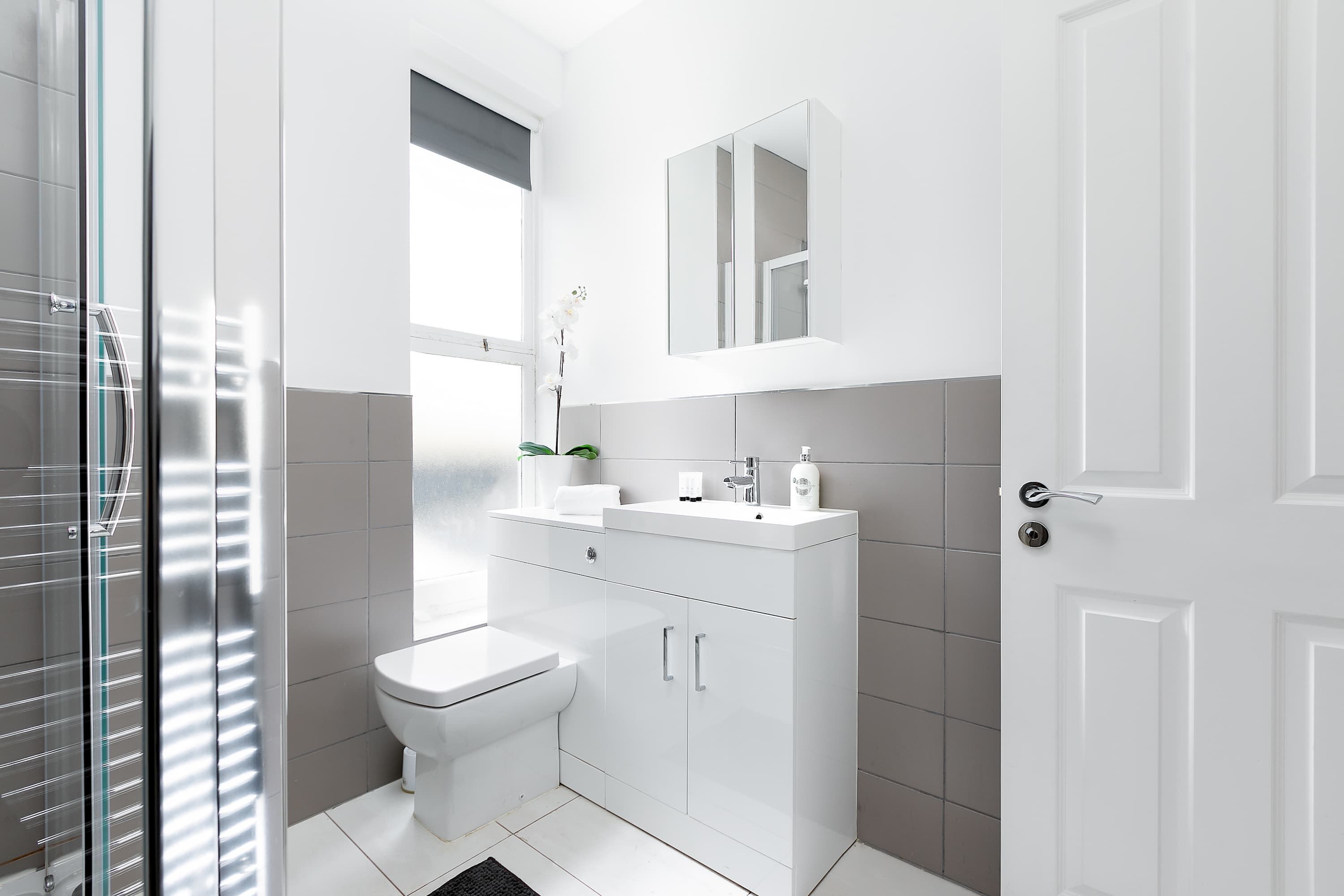 A modern bathroom with a toilet, sink, and mirror.