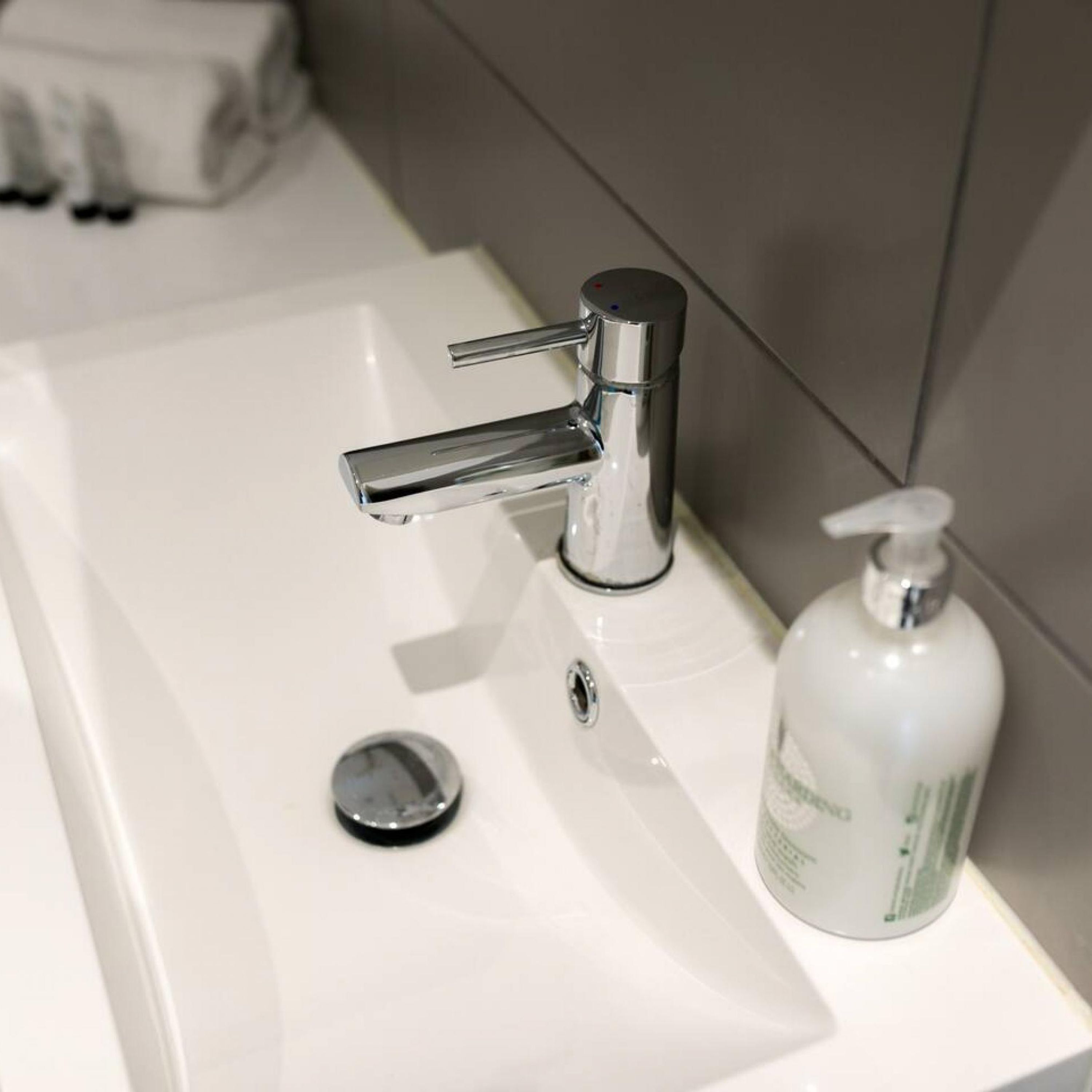 A bathroom sink with a chrome faucet and a soap dispenser.
