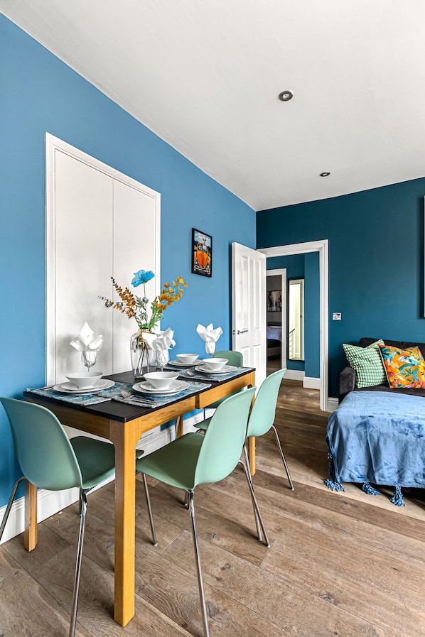 A dining area with a table set for four, two chairs, a vase with flowers, and a door leading to another room.