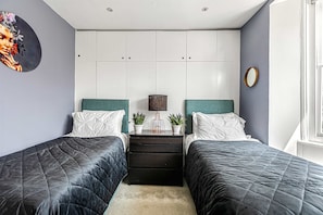 A bedroom with two beds, a dresser, a lamp, and a mirror.
