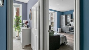 A modern kitchen with white cabinets and a dining area with a table and chairs. - The Lanes Comfy Condo Walk to Beach King Bed (Brighton)