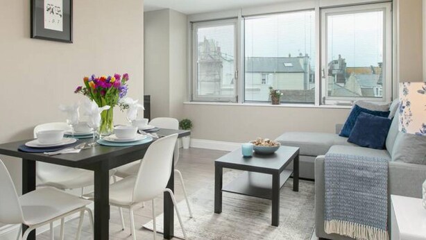A modern living room with a dining area, large windows, and a view of the city. - Spacious Perfect Location Moments Away From Pier (Brighton)