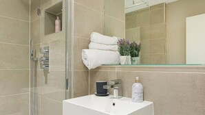 A modern bathroom with a glass shower enclosure, a white vanity, and a mirror above the sink. - Spacious Perfect Location Moments Away From Pier (Brighton)