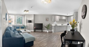 Un salon moderne comprenant un canapé, une table à manger et un coin cuisine avec des placards et un évier.