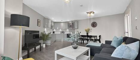 Een moderne woonkamer met een bank, salontafel en een eethoek met stoelen.
