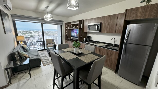 A modern kitchen with a dining area, a built-in oven, and a refrigerator. - Beautiful Appartment in front of the TSM Stadium (Torreon)
