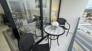 A balcony with two wicker chairs, a small round table with a vase of flowers, and a glass partition. - Beautiful Appartment in front of the TSM Stadium (Torreon)