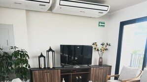 A modern living room with a grey sofa, a round coffee table, a TV, and a plant. - Beautiful Appartment in front of the TSM Stadium (Torreon)