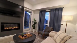 Una sala de estar moderna con chimenea, un sofá, un sillón y una mesa de centro.