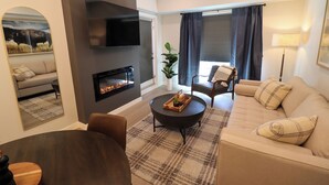 Una sala de estar moderna con chimenea, sofá, mesa de centro y televisor.