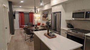 Una cocina moderna con una isla central, electrodomésticos de acero inoxidable y un comedor con una mesa redonda y sillas.