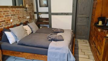Una camera da letto con un letto di legno, un muro in mattoni, uno specchio e un armadio in legno.