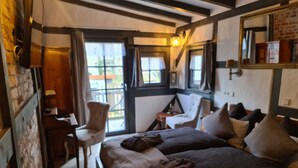 A cozy room with two beds, a desk, and a chair. There are windows with curtains, a lamp, and a mirror on the wall. - Hotel b&b altes hinterhäusel  (Freiberg)