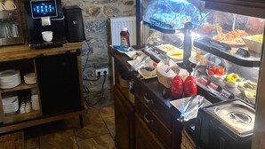 A breakfast buffet with a coffee machine, a variety of food items, and a stone wall background. - Hotel b&b altes hinterhäusel  (Freiberg)