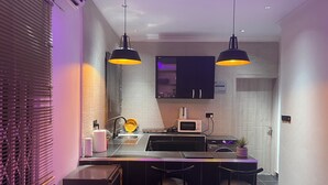 Una cocina moderna con una isla central, taburetes de bar, un microondas y un fregadero.