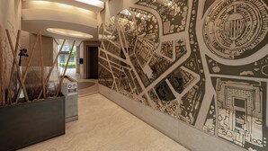 Eine moderne Lobby mit einer großen Wandmalerei, einem Empfangsbereich und einer Pflanzengruppe.