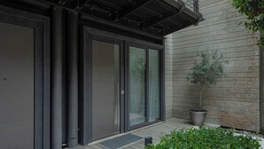 Ein modernes Gebäude mit großen Schiebeglastüren, einem Blumentopf und einer Holzterrasse.