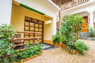 Un patio con cerca de madera, plantas en macetas y un camino de grava.