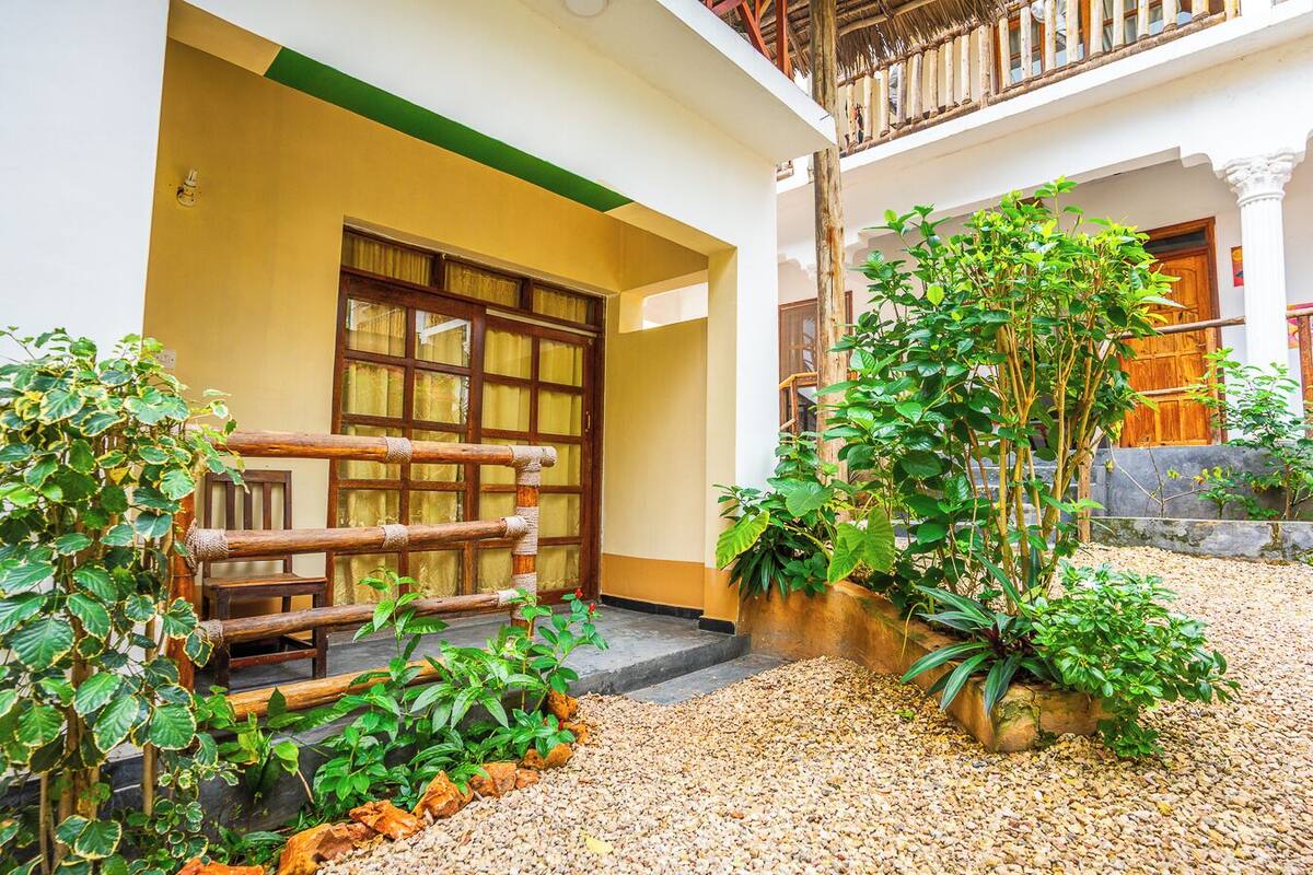 Un patio con cerca de madera, plantas en macetas y un camino de grava.
