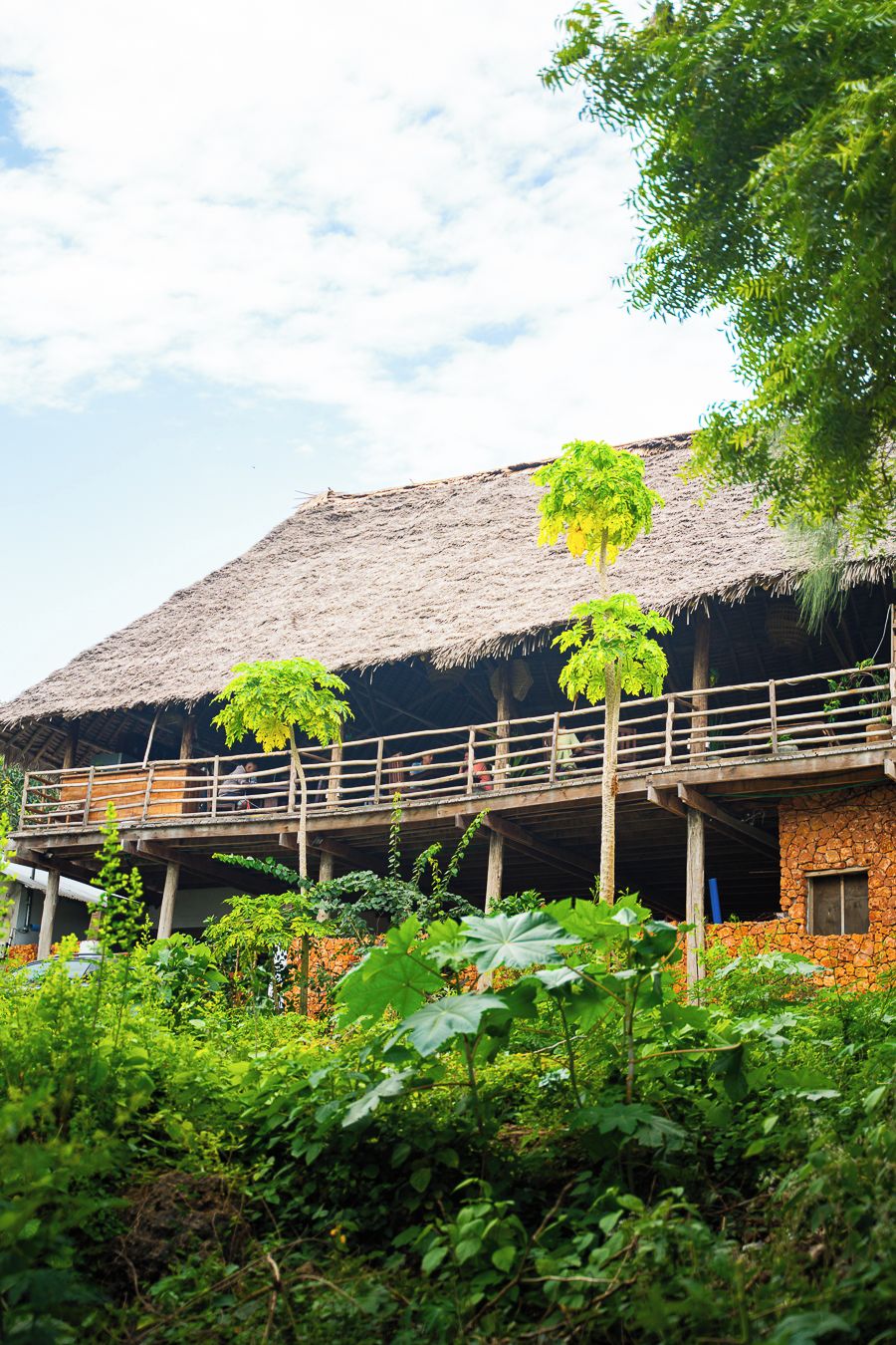 A thatched-roof building with a balcony and a stone wall.