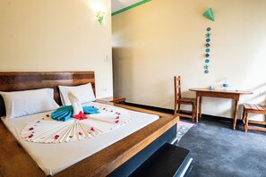 Habitación de hotel con una cama de madera, una pequeña mesa con sillas y una pared decorada.