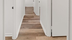 Ein Flur mit weißen Wänden, Holzboden und einer Deckenleuchte.