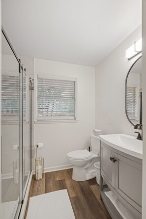 A bathroom with a toilet, sink, and shower area.