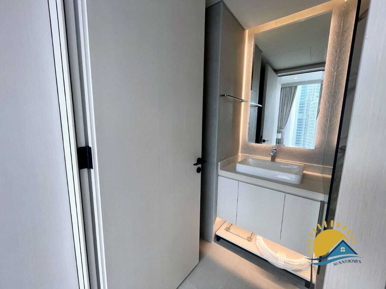 Une salle de bain moderne avec un grand miroir, un lavabo blanc et un espace douche.