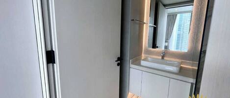 Une salle de bain moderne avec un grand miroir, un lavabo blanc et un espace douche.