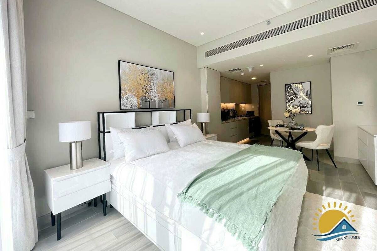 Een moderne hotelkamer met een groot bed, nachtkastjes, een bureau en een stoel.